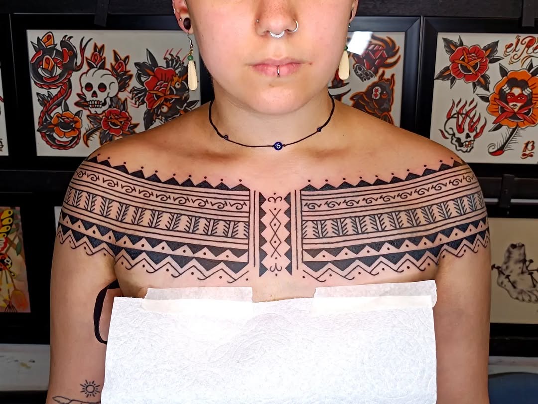 Filipino tribal chest and shoulder tattoo in progress, studio flash art sheets on wall